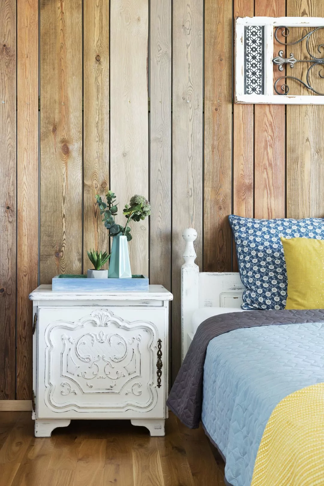 Kolorowe mieszkanie,mieszkanie boho,dekoracja nad łóżkiem panel drewniany,ściana obita drewnianymi dechami w kolorze drewna, niebieskie kinkiety vintage, rzeźbione fronty szafek nocnych w kolorze białym