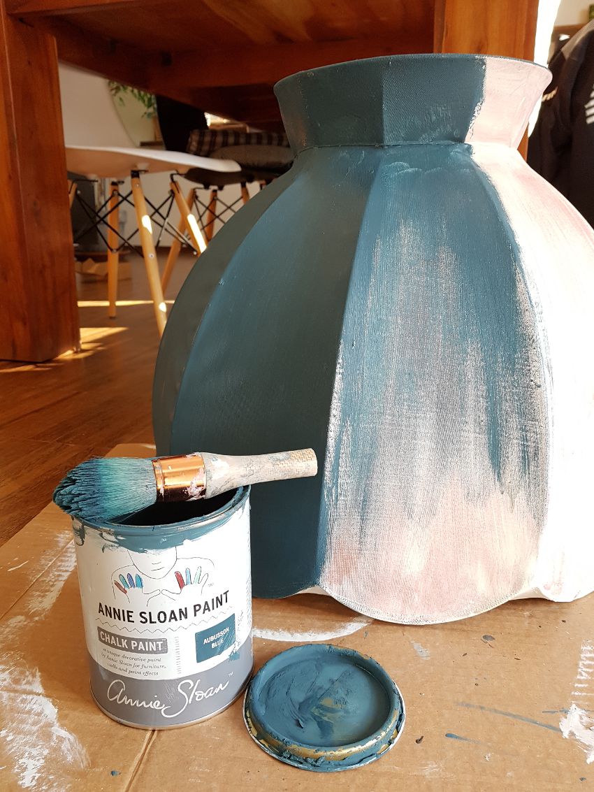 jak odnowić lampę, malowanie abażuru, farby kredowe Annie Sloan, Aubusson Blue, abażur leży na podłodze w trakcie jego malowania, obok leży puszka z farbą i pędzel, w tle drewniany stół