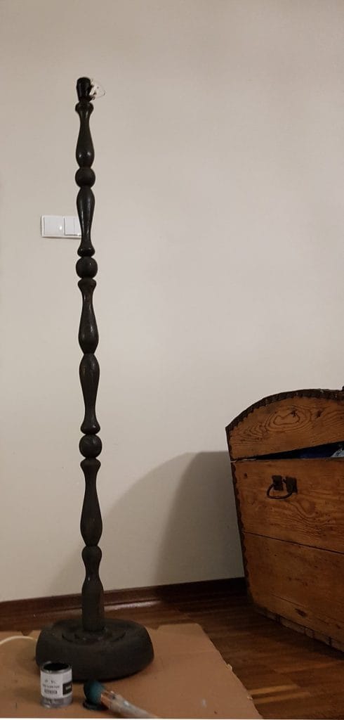 Jak odnowić lampę, podstawa lampy podłogowej pomalowana na czarno, na podłodze leży puszka z farbą i pędzel, w tle stary drewniany kufer, Renowacja mebli, metamorfoza starych mebli, renowacja mebli warszawa, stare meble w stylu boho, metamorfoza mebli vintage, stare meble vintage po renowacji, renowacja ram i mebli warszawa, przerabianie mebli vintage, renowacja mebli vintage, jak odnowić stary abażur, jak odnowić abażur, jak odnowić lampę stojącą, jak pomalować abażur, jak odnowić starą lampę, czy można pomalować abażur,