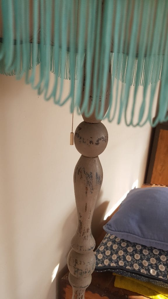 jak odnowić lampę, widoczny kawałek abażuru z niebieskimi frędzlami, w tle podstawa lampy z licznymi przetarciami i niebieskie poduszki