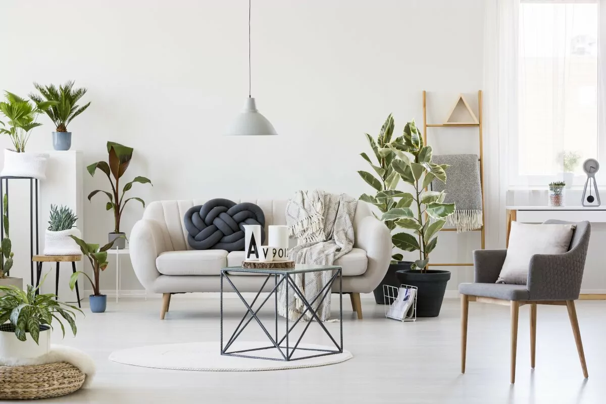 Jak nie urządzać mieszkania,Przemysłowy stolik kawowy pośrodku skandynawskiego wnętrza salonu z białą sofą, szarym krzesłem, dużą iloscią roślin doniczkowych
