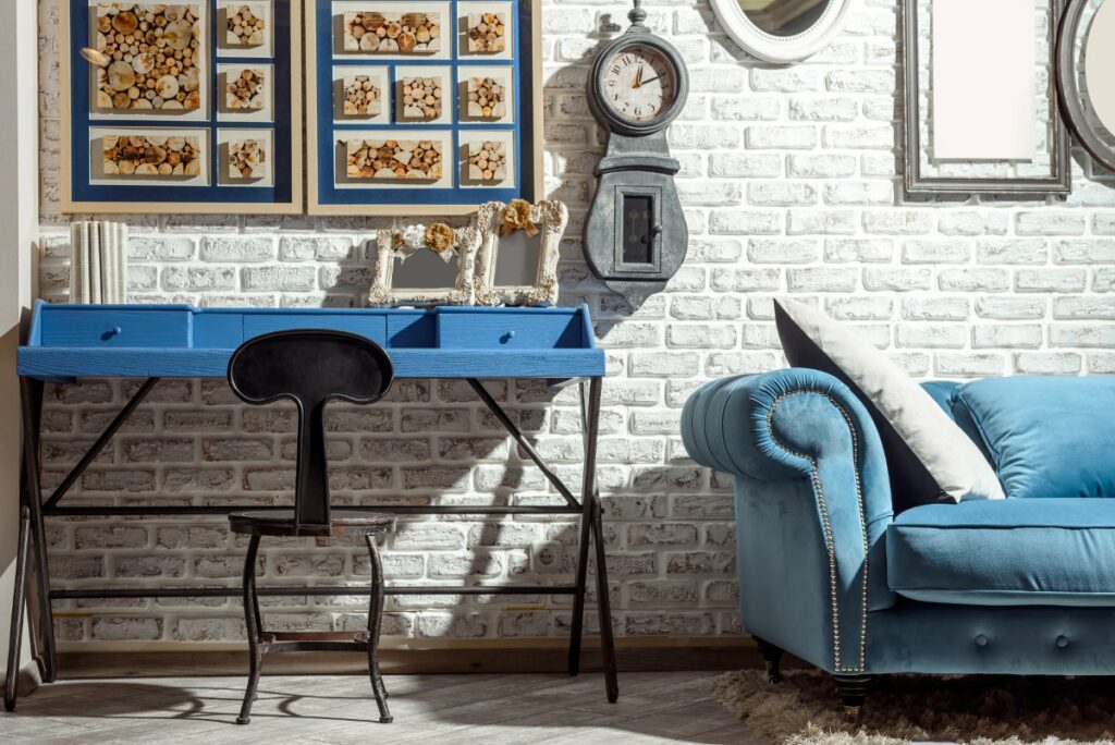 Dlaczego projektant wnętrz, Ściana z białej cegły na jej tle niebieska kanapa i niebieskie biurko, loftowy stołek biurowy