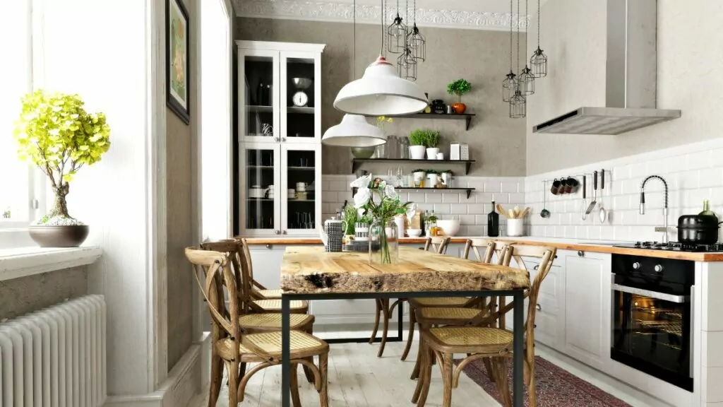 Jasne wnętrza, Kuchnia w stylu rustykalnym, tradycyjne białe szafki kuchenne, szara ściana, przeszklona tradycyjna kuchenna witryna, Drewniany stół na środku kuchni z grubym dębowym blatem, krzesła przy stole tradycyjne z plecionym siedziskiem
