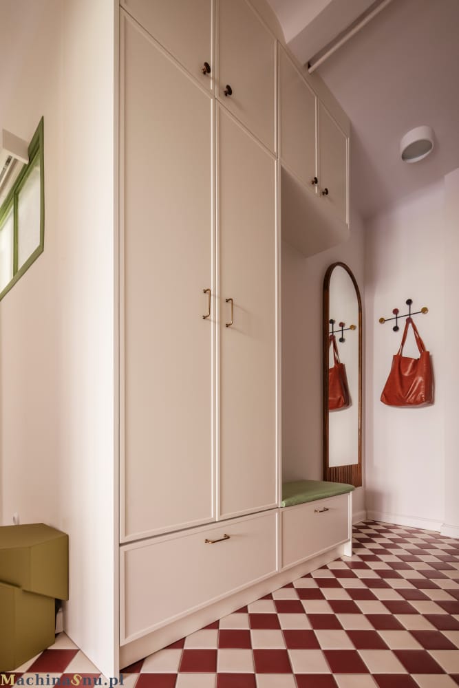 Nowoczesne mieszkanie w stylu PRL- Warszawa Muranów 10 Pierwsze wrażenie ma znaczenie. Ten przedpokój od progu komunikuje odważny charakter całego mieszkania. Zaprojektowana na wymiar szafa jest nie tylko pojemnym schowkiem, ale i ciekawym nawiązaniem so przeszłości. Duże lustro i minimalistyczne detale optycznie powiększają przestrzeń, udowadniając, że nawet czysto funkcjonalne pomieszczenie może być źródłem codziennej inspiracji. To idealne wprowadzenie do domu, w którym każdy detal został starannie przemyślany.